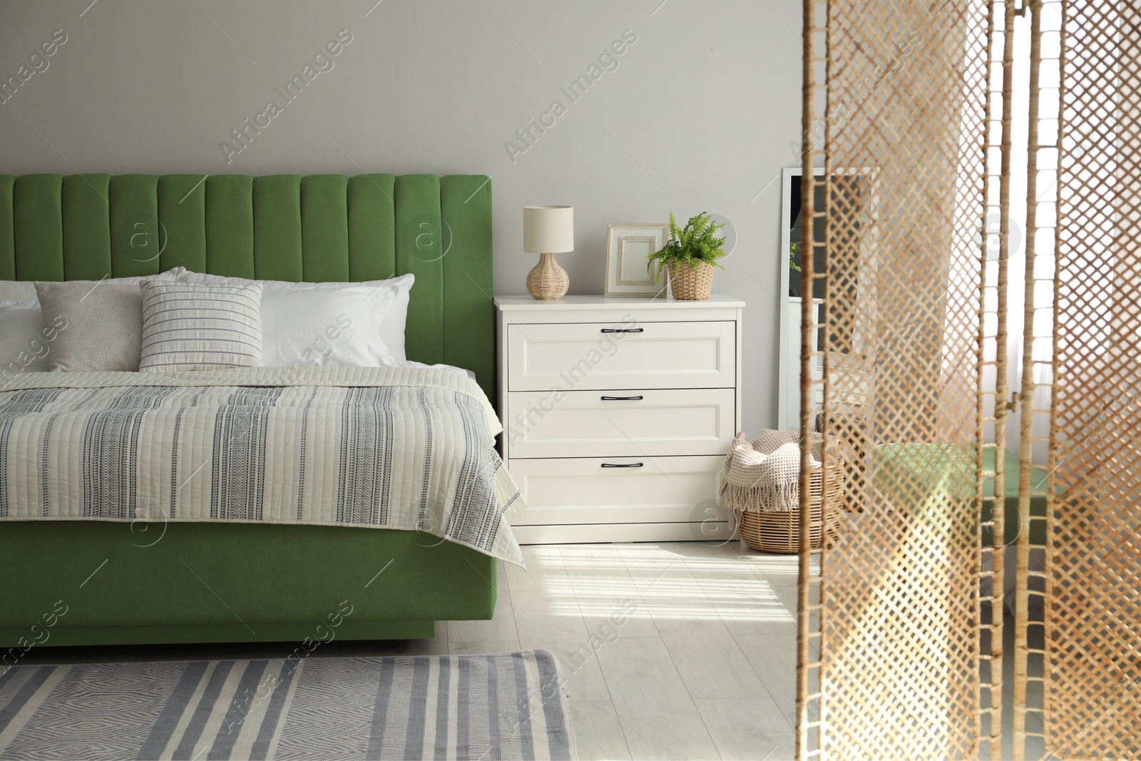 Image of Comfortable bed and chest of drawers in room. Interior design