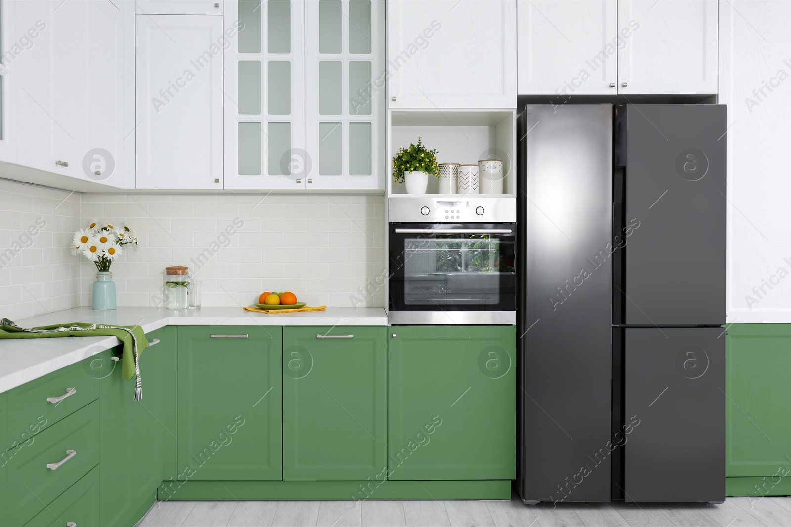 Image of Stylish furniture and modern refrigerator in kitchen. Interior design