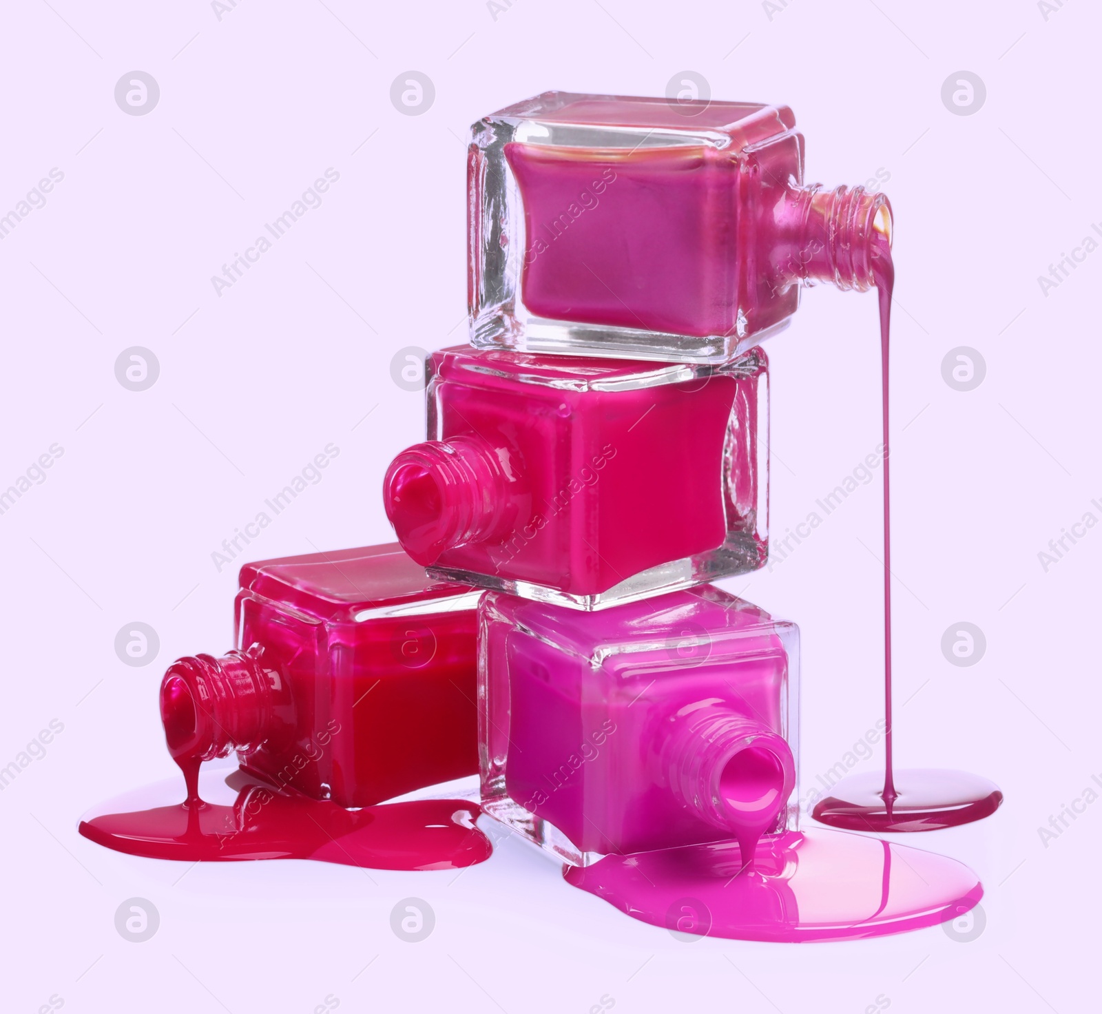 Image of Different nail polishes dripping from open bottles on light background