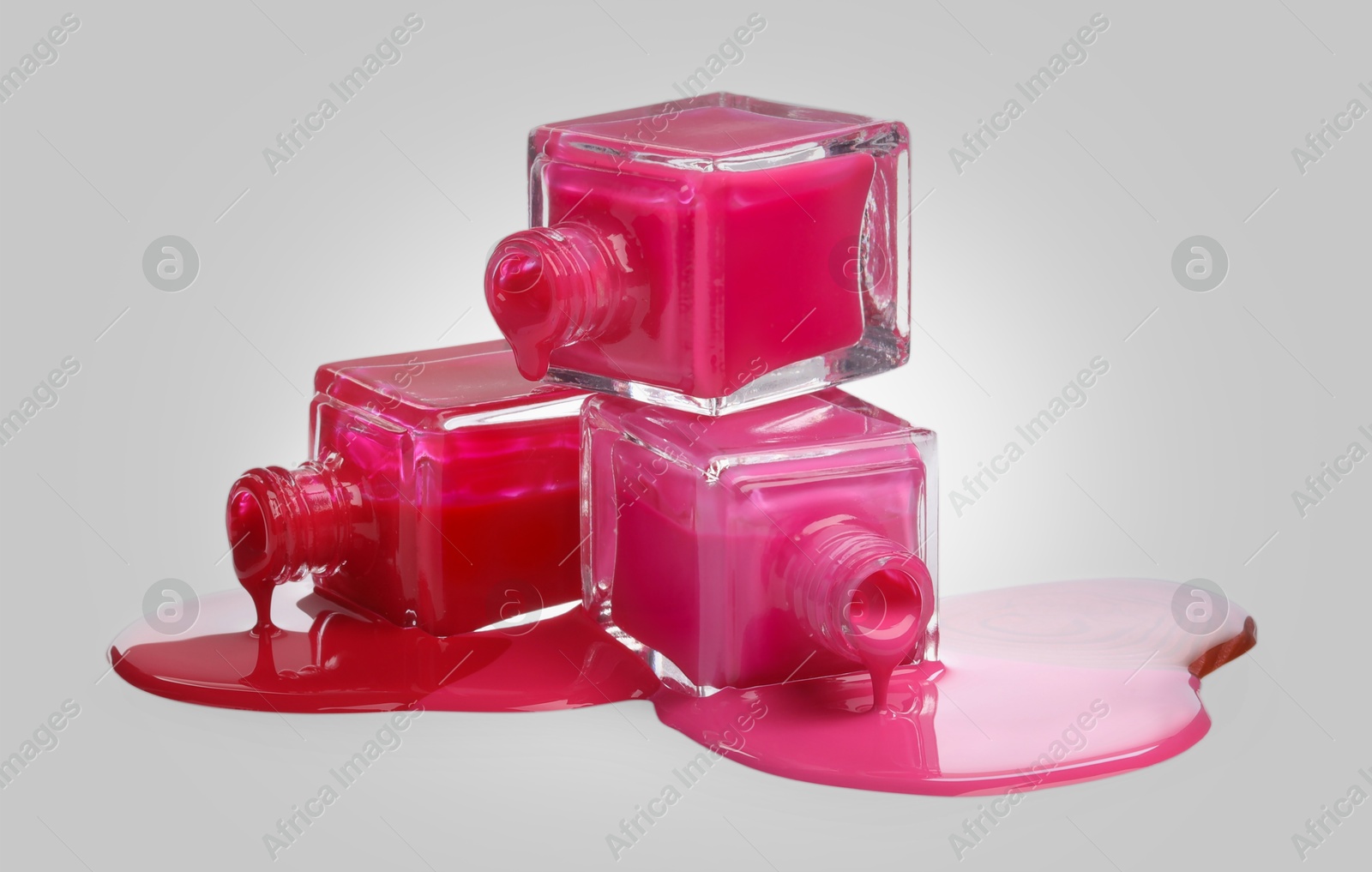 Image of Different nail polishes dripping from open bottles on light background