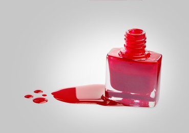 Spilled red nail polish and bottle on light background. Space for text