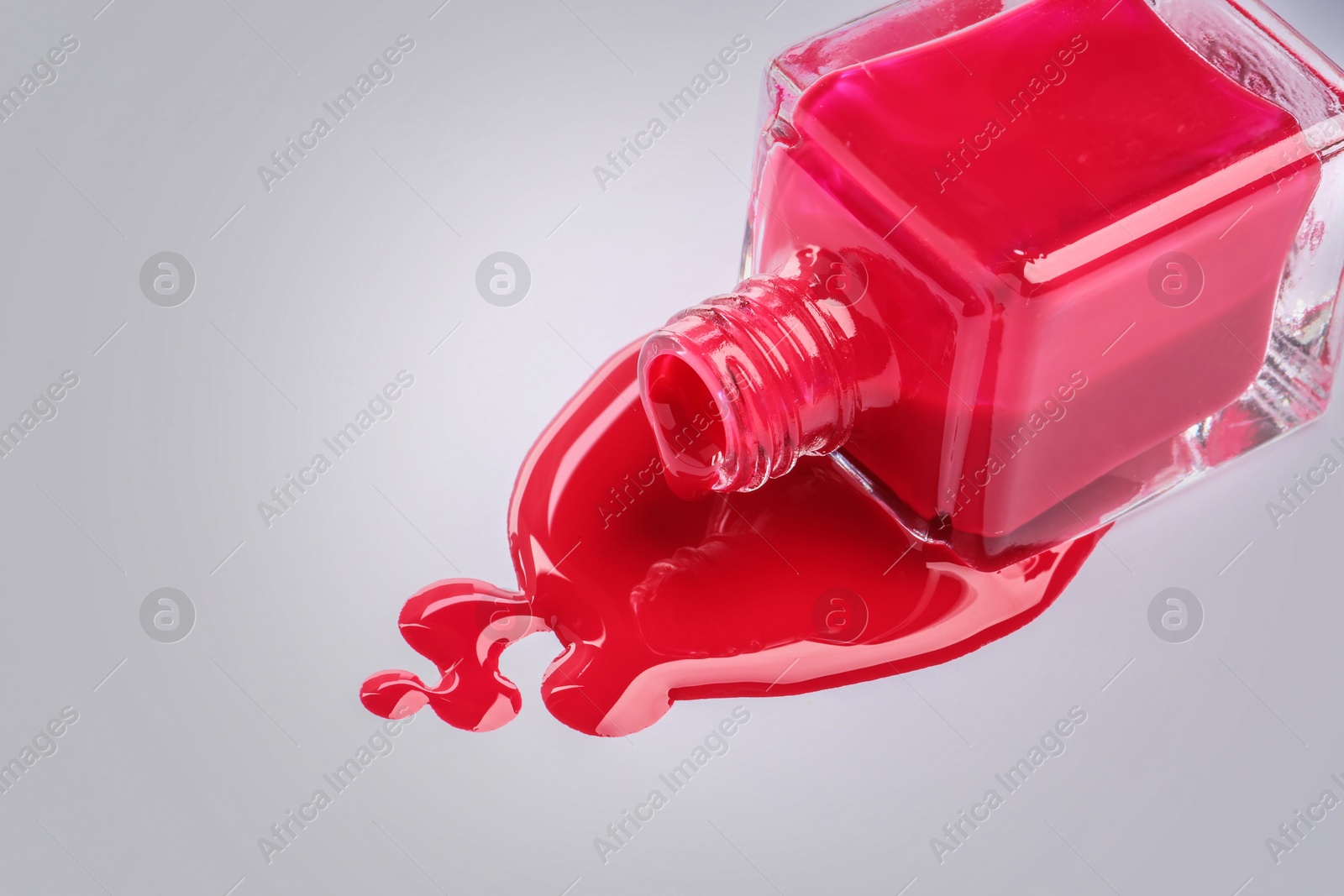 Image of Spilled red nail polish and bottle on light grey background, closeup. Space for text