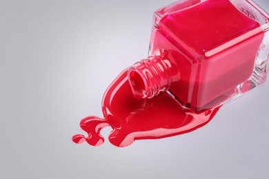 Image of Spilled red nail polish and bottle on light grey background, closeup. Space for text