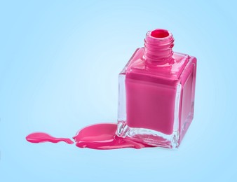 Spilled pink nail polish and bottle on light blue background. Space for text
