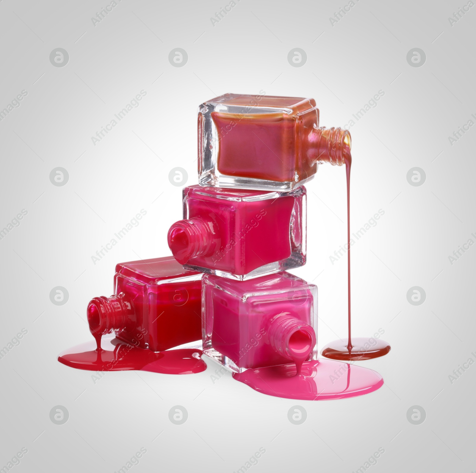 Image of Different nail polishes dripping from open bottles on light background