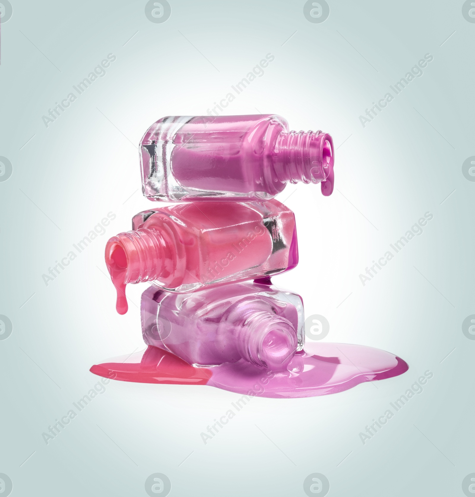 Image of Different nail polishes dripping from open bottles on light background