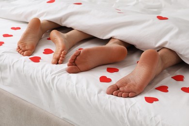 Couple lying in bed with red hearts, closeup