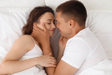 Lovely couple spending time together in bed at morning, top view