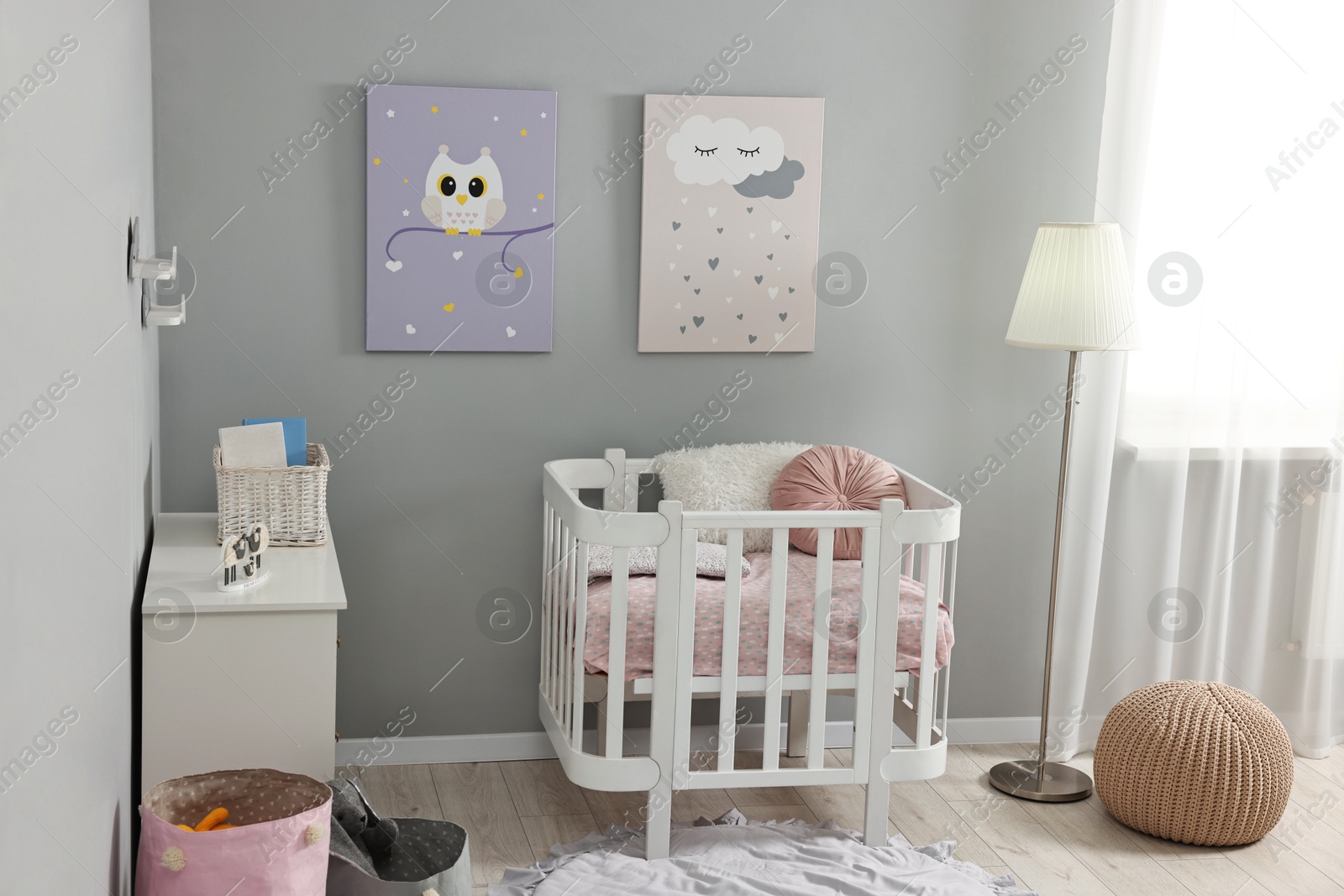 Photo of Newborn baby room interior with stylish furniture, comfortable crib and pictures of on wall