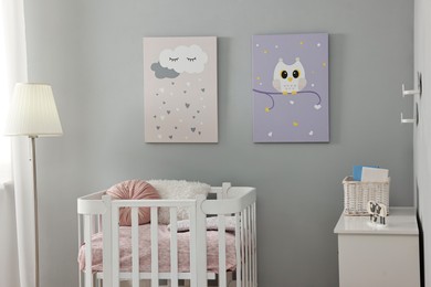 Newborn baby room interior with stylish furniture, comfortable crib and pictures of on wall