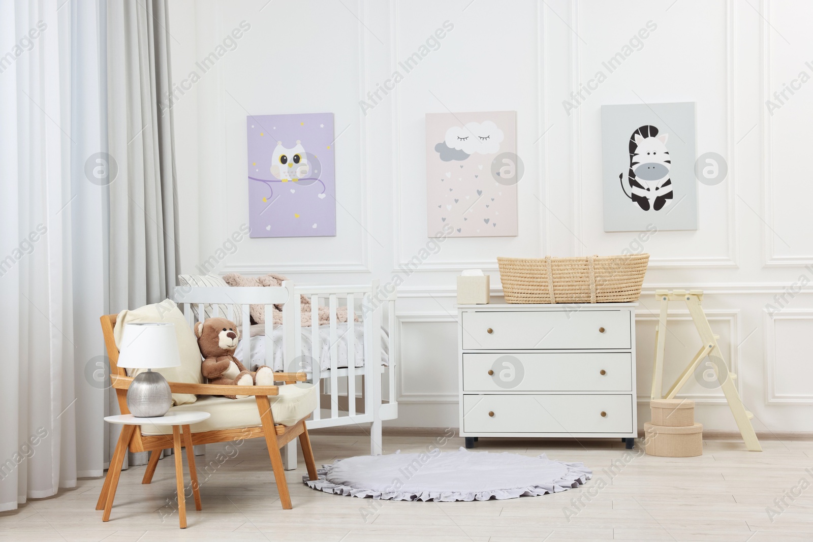 Photo of Newborn baby room interior with stylish furniture, comfortable crib and pictures of on wall