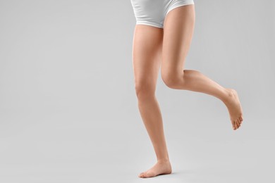 Woman with slim legs on grey background, closeup