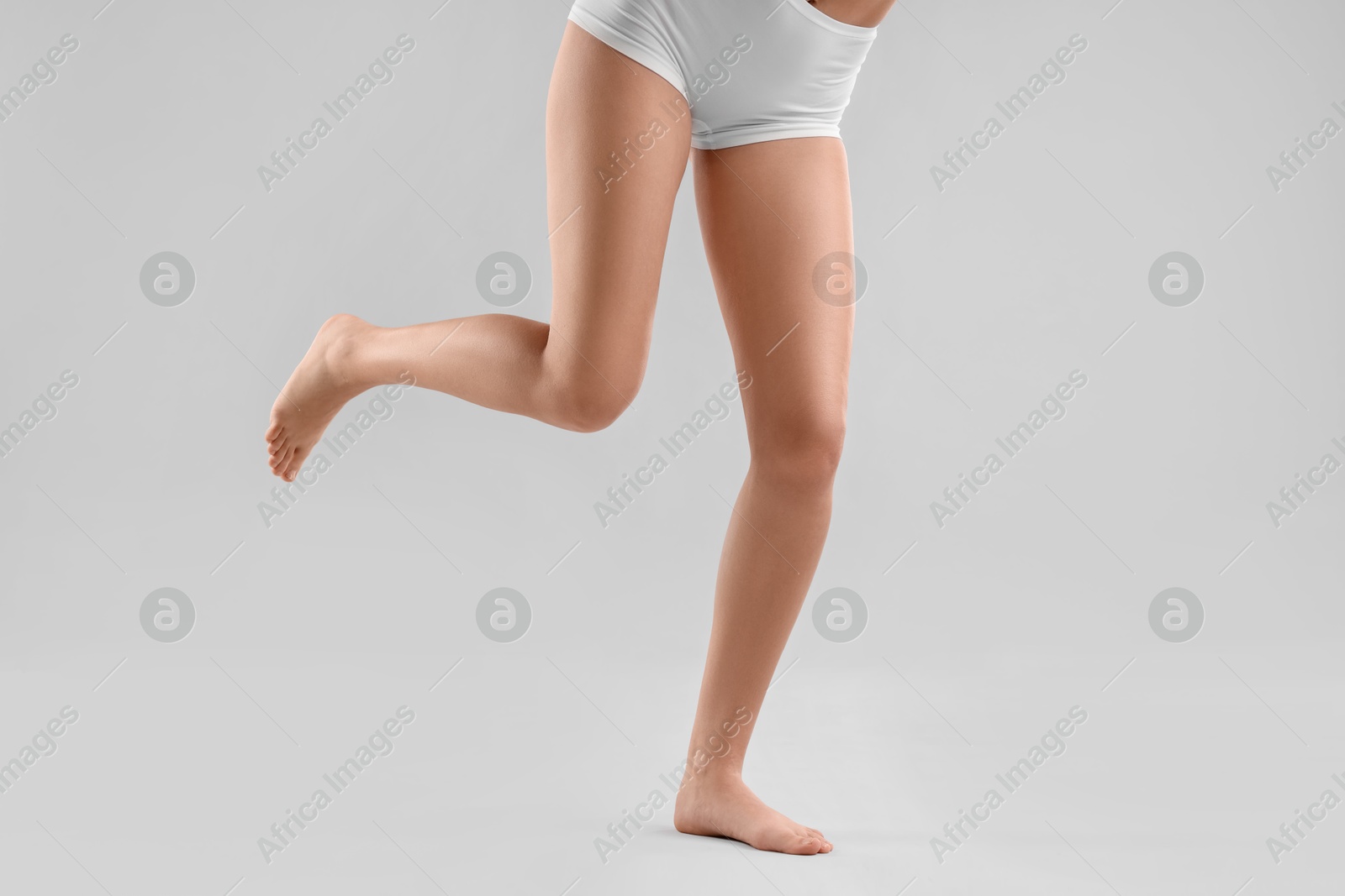 Photo of Woman with slim legs on grey background, closeup