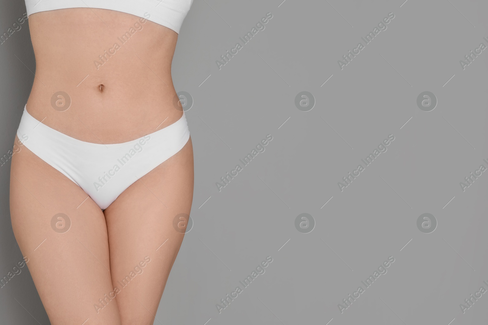 Photo of Woman with slim body posing on grey background, closeup. Space for text