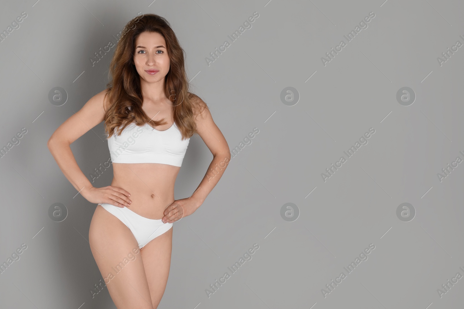 Photo of Woman with slim body posing on grey background, space for text