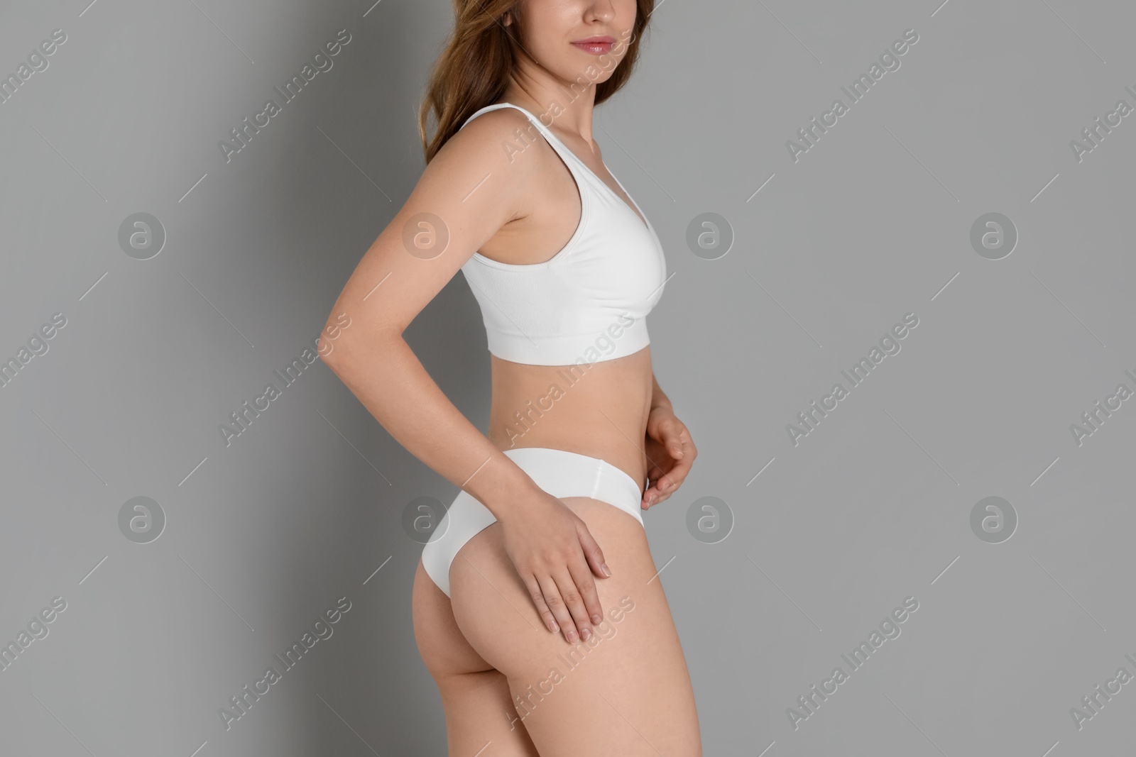 Photo of Woman with slim body posing on grey background, closeup