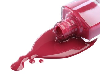 Bottle and spilled pink nail polish isolated on white