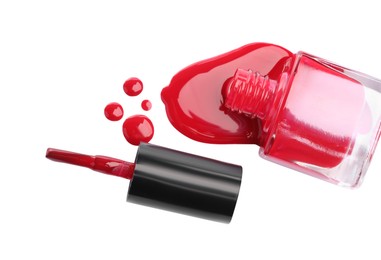 Photo of Bottle and brush with spilled red nail polish isolated on white, top view