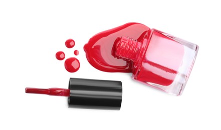 Photo of Bottle and brush with spilled red nail polish isolated on white, top view