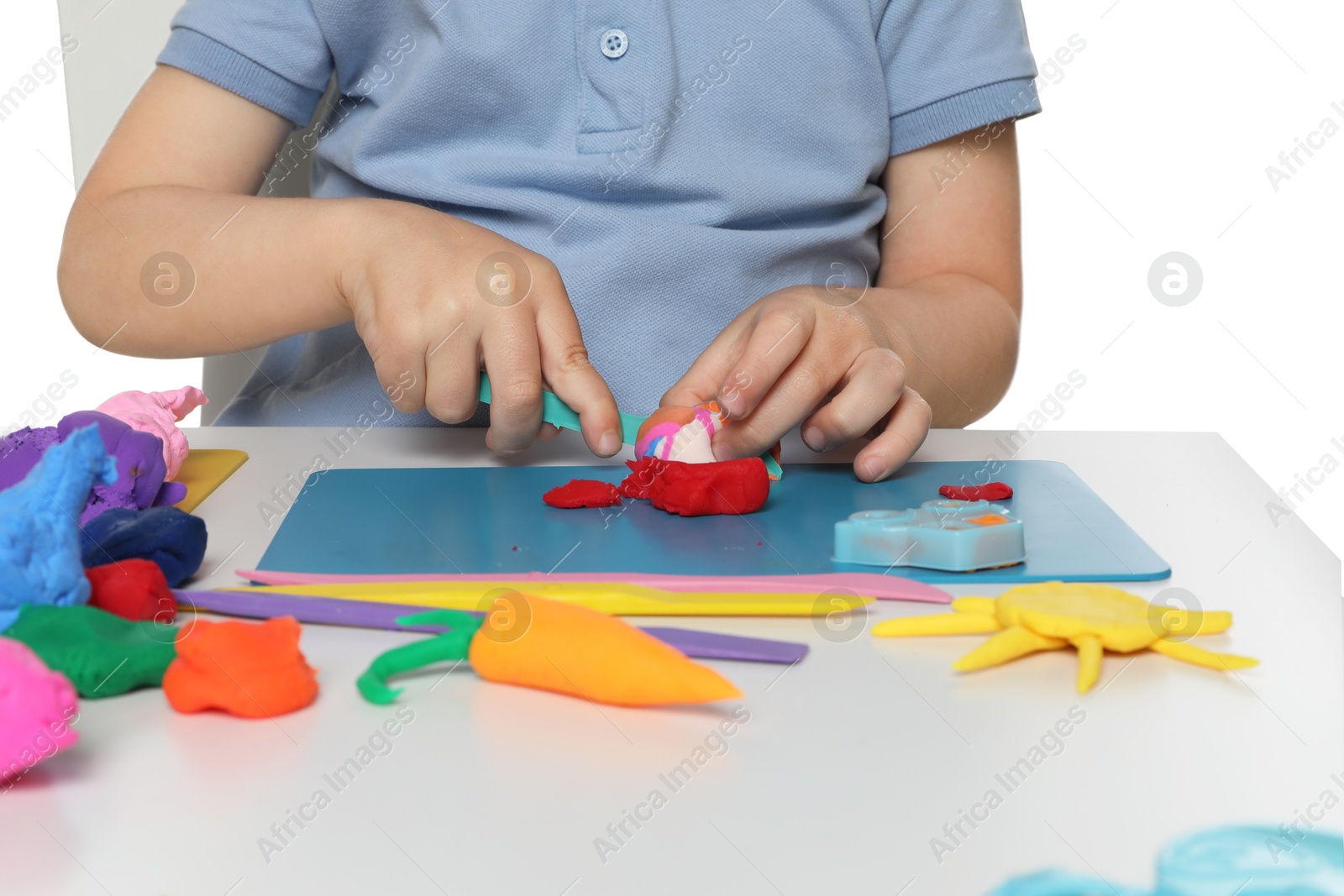 Photo of Little boy sculpting with play dough at table on white background, closeup