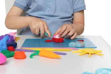 Little boy sculpting with play dough at table on white background, closeup