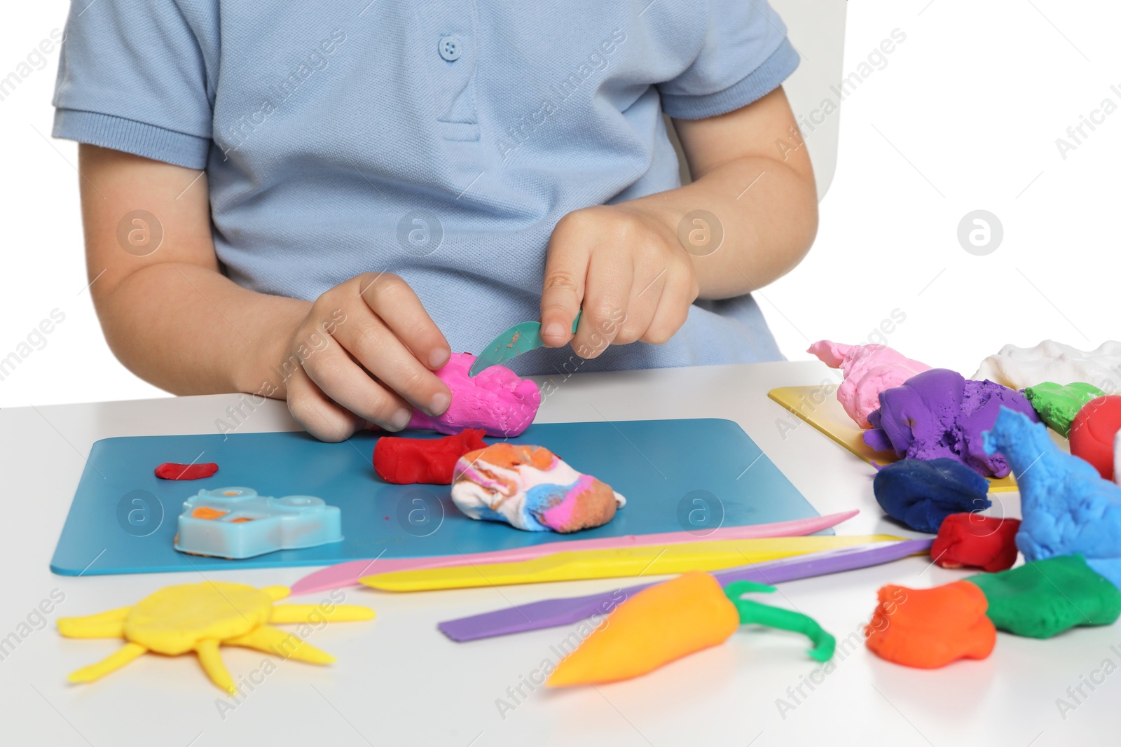 Photo of Little boy sculpting with play dough at table on white background, closeup