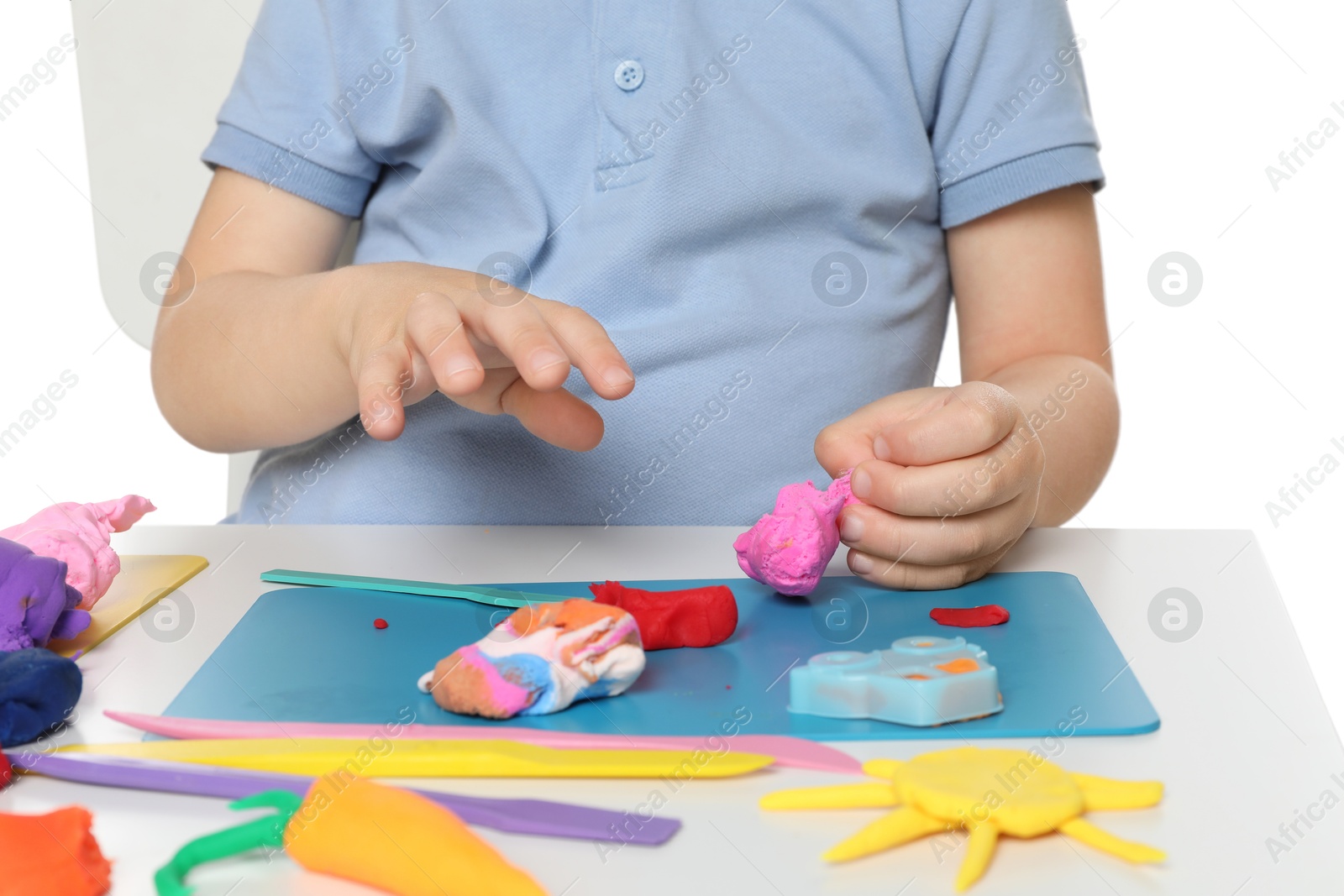 Photo of Little boy sculpting with play dough at table on white background, closeup