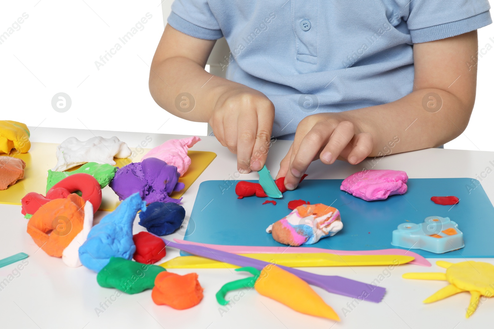 Photo of Little boy sculpting with play dough at table on white background, closeup