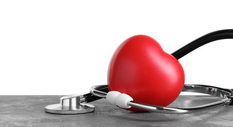 Photo of Stethoscope and red heart on grey table against white background, space for text