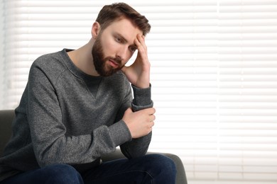 Photo of Loneliness concept. Sad man sitting on sofa at home, space for text