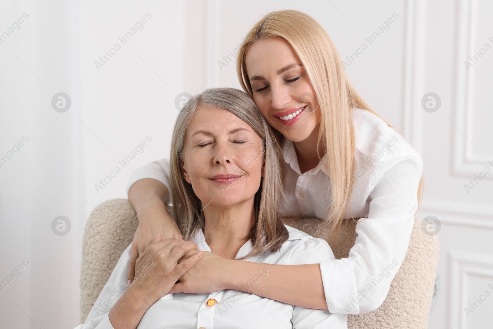 Photo of Family portrait of young woman and her mother near white wall