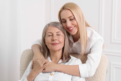 Family portrait of young woman and her mother near white wall