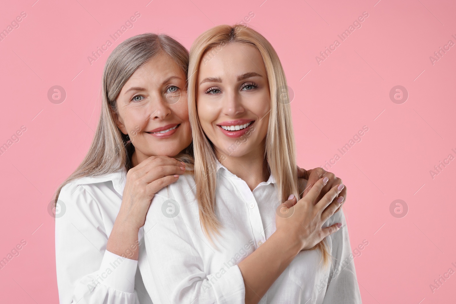 Photo of Family portrait of young woman and her mother on pink background