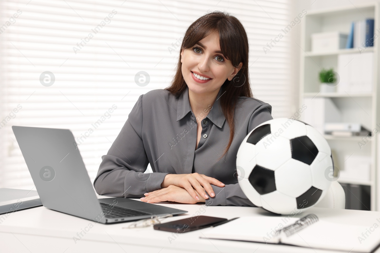 Photo of Smiling employee with soccer ball at table in office