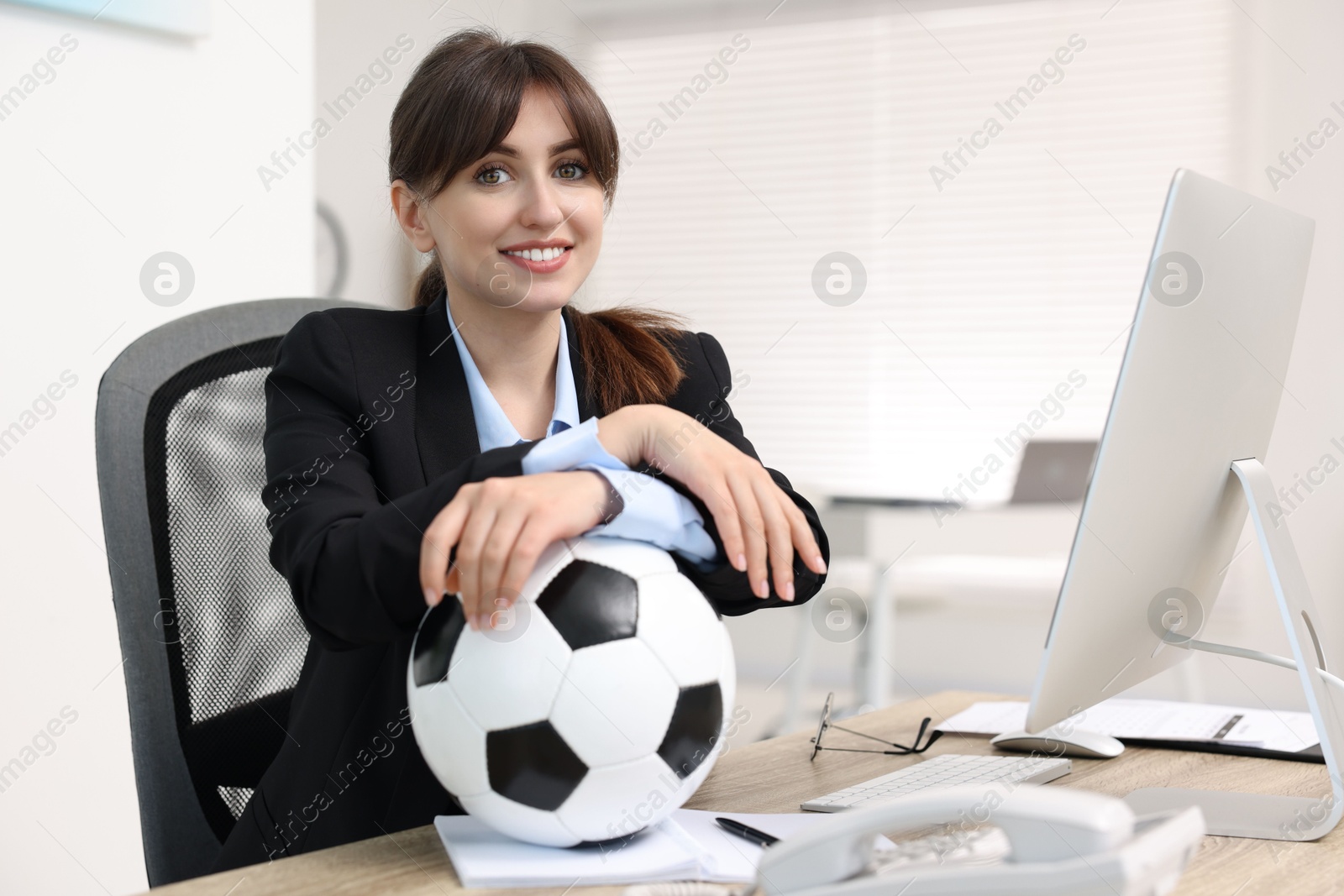 Photo of Smiling employee with soccer ball at table in office