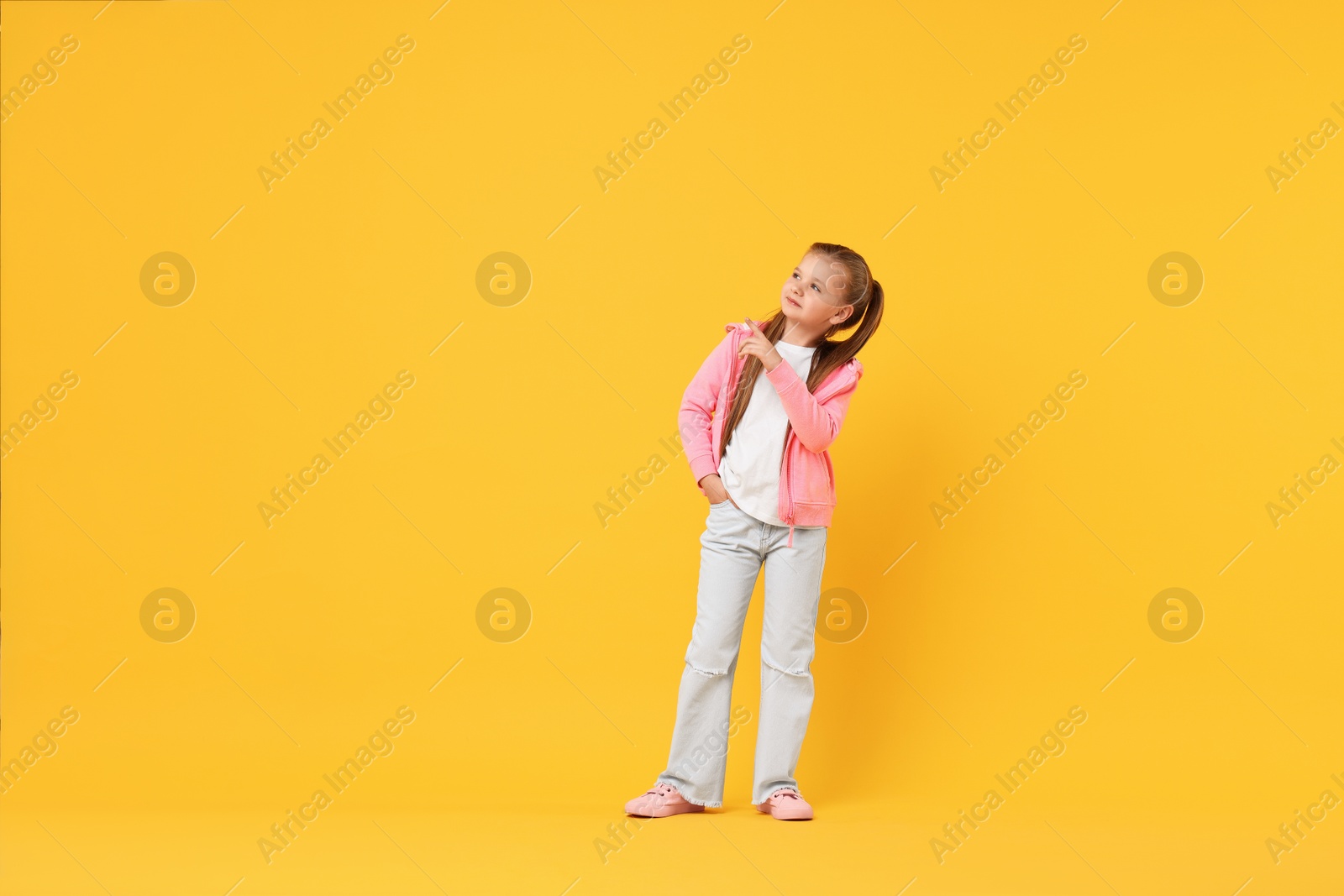 Photo of Cute little girl dancing on yellow background, space for text