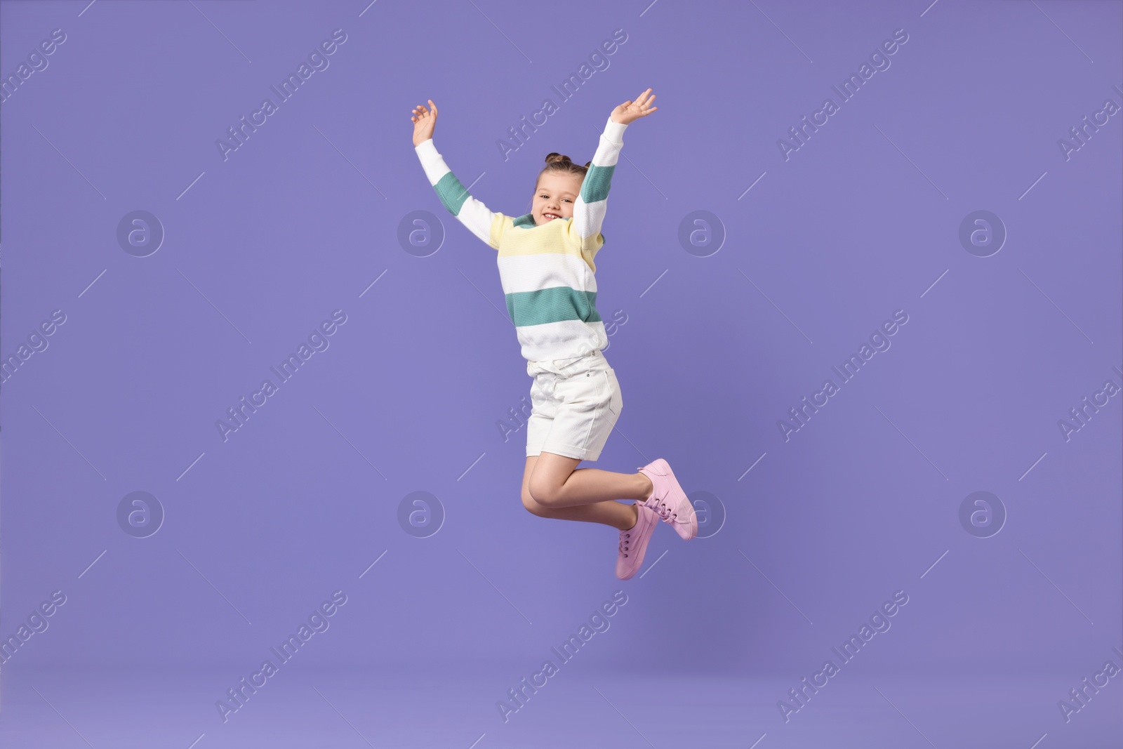 Photo of Cute little girl dancing on violet background
