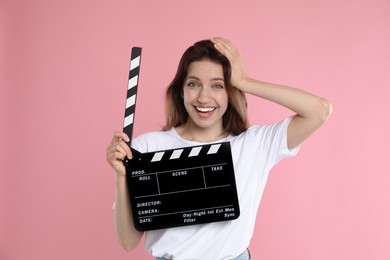 Photo of Making movie. Smiling woman with clapperboard on pink background