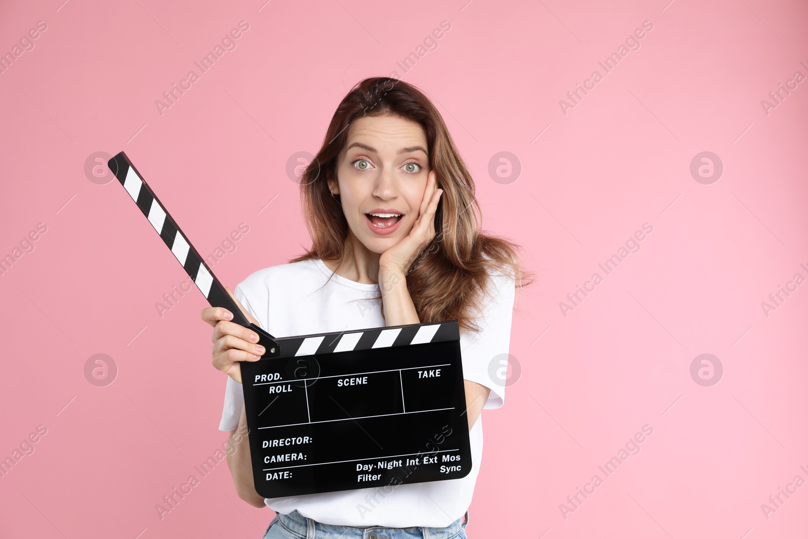 Photo of Making movie. Surprised woman with clapperboard on pink background