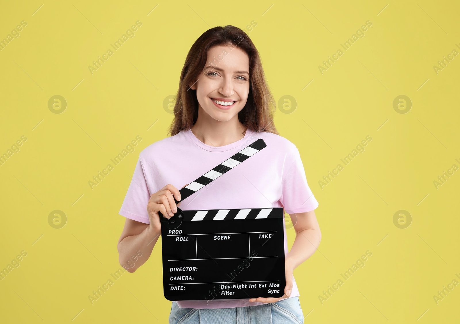 Photo of Making movie. Smiling woman with clapperboard on yellow background