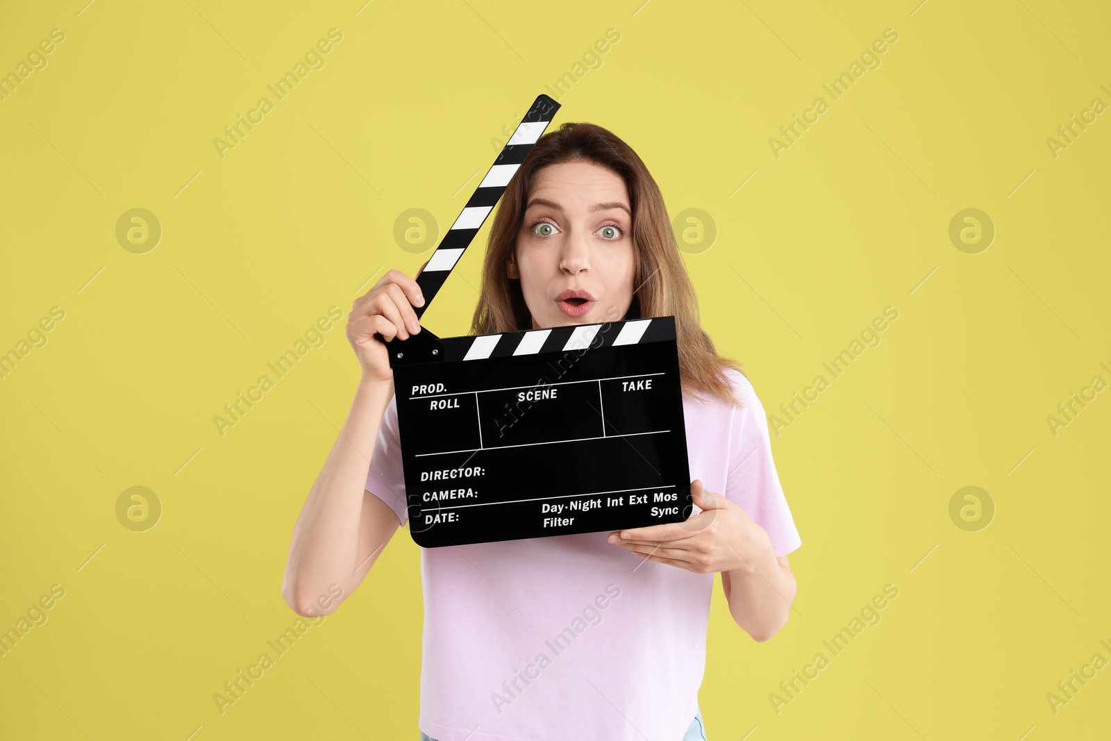 Photo of Making movie. Surprised woman with clapperboard on yellow background