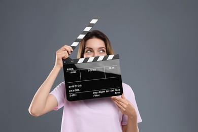 Photo of Making movie. Woman with clapperboard on grey background