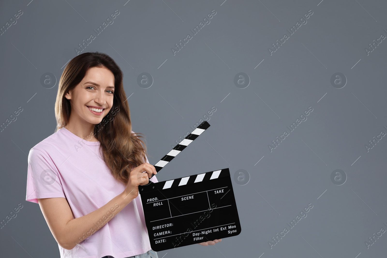 Photo of Making movie. Smiling woman with clapperboard on grey background. Space for text