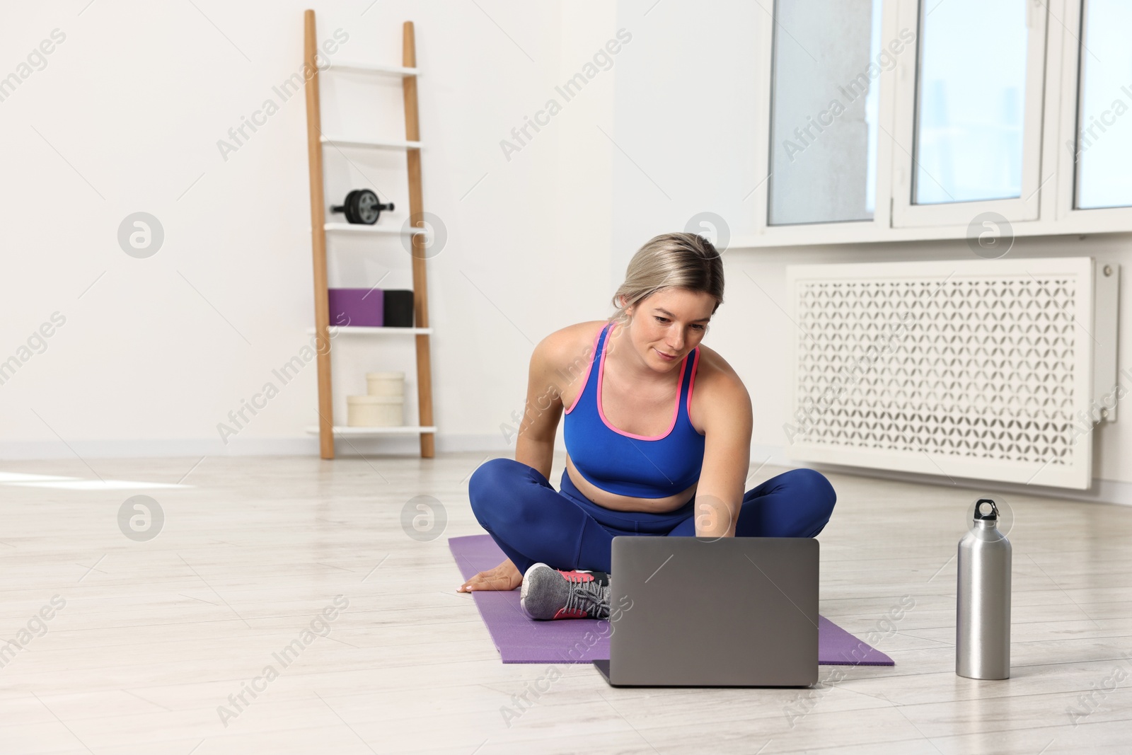 Photo of Online fitness trainer. Woman watching tutorial on laptop at home