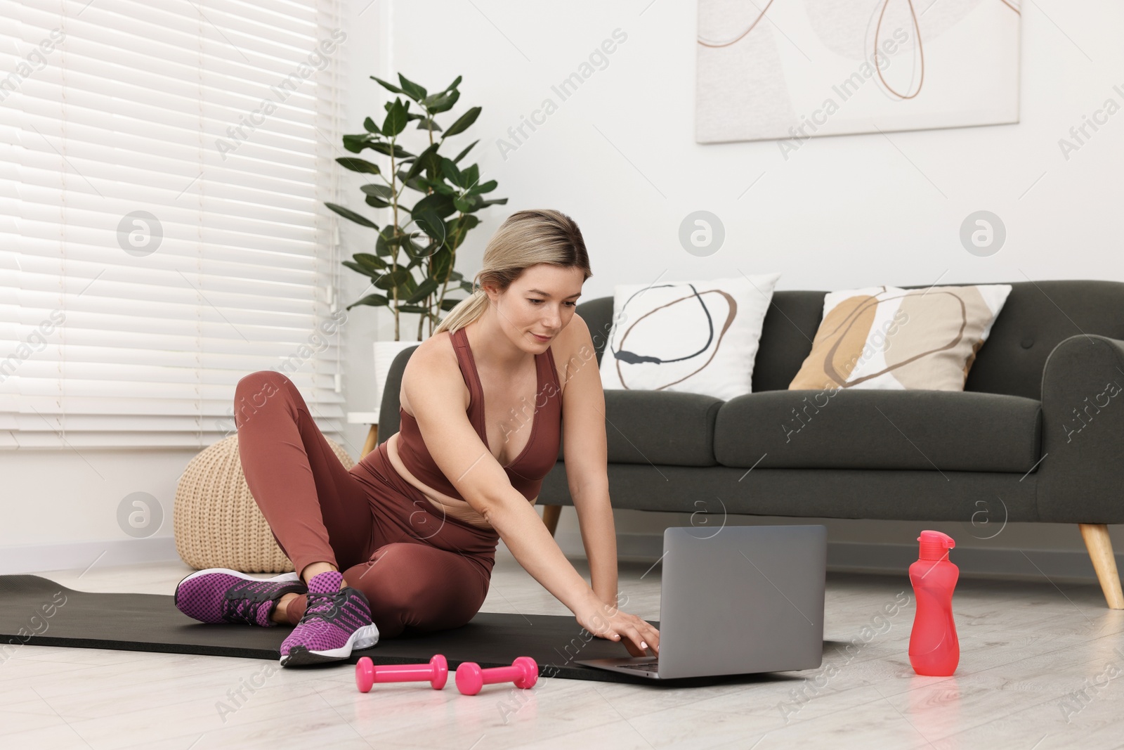 Photo of Online fitness trainer. Woman watching tutorial on laptop at home