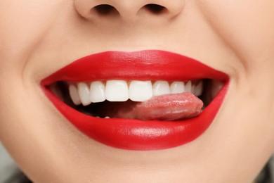 Woman with red lipstick showing her tongue, closeup