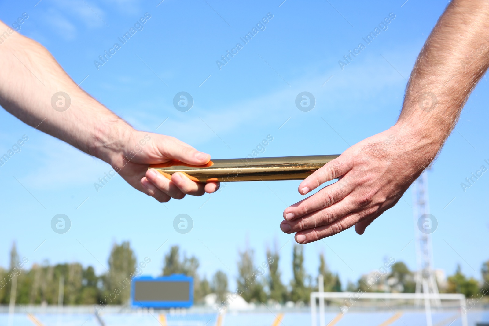 Photo of Man passing baton to his partner at stadium, closeup