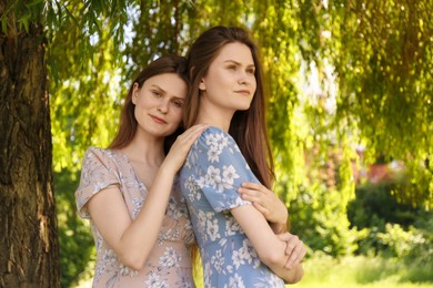 Portrait of two beautiful twin sisters in park
