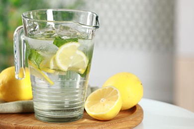 Refreshing lemonade with mint in jug and citrus fruits on white table, closeup. Space for text