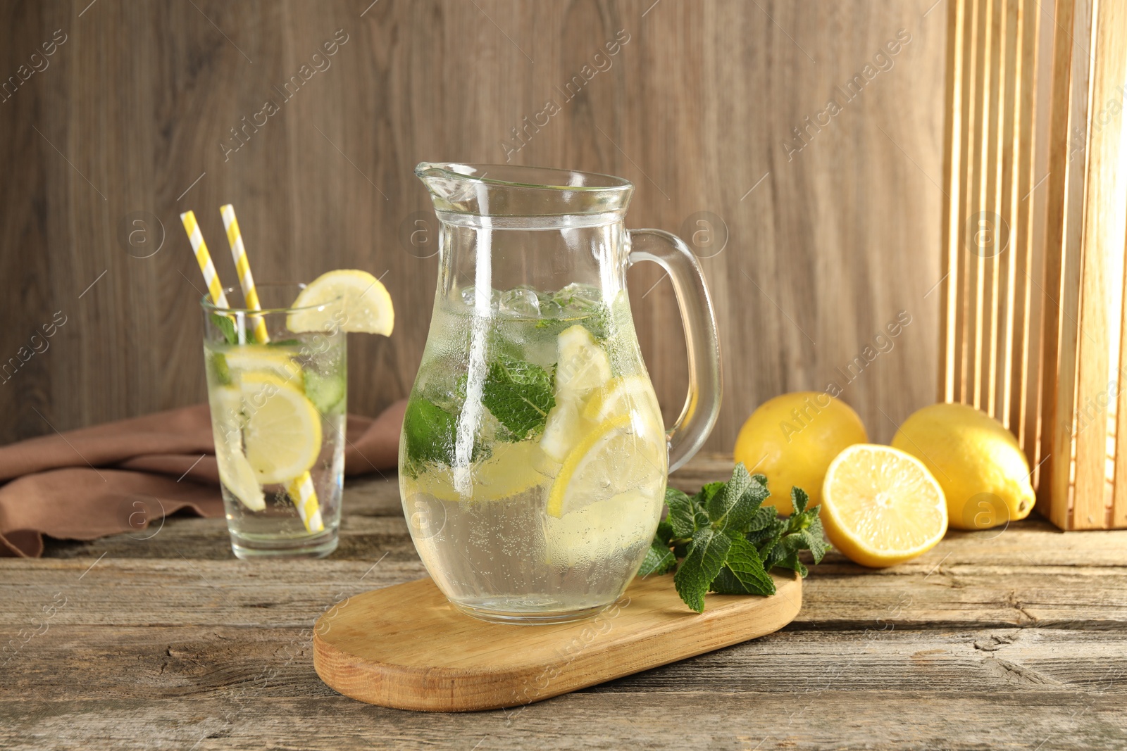 Photo of Refreshing lemonade with mint in jug and glass on wooden table